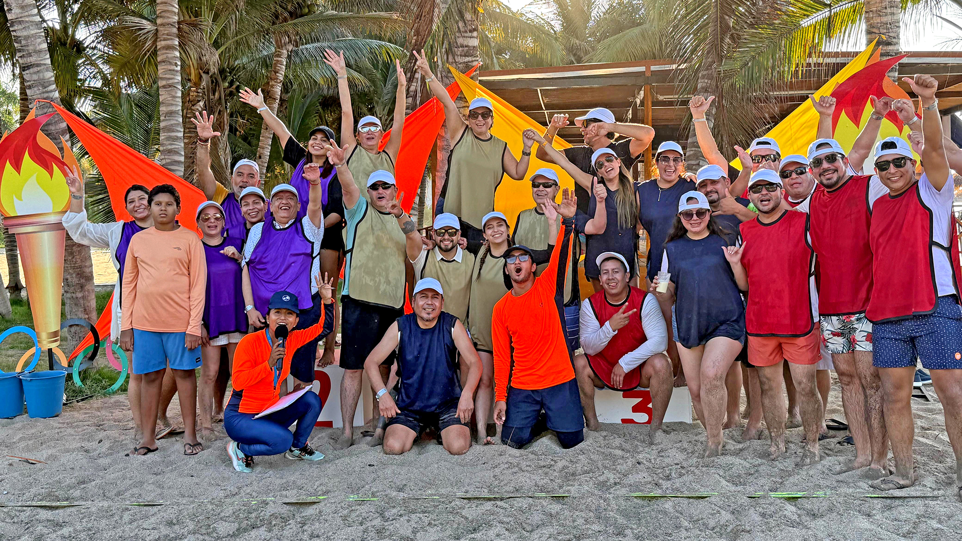 Heel Ecuador Mitarbeiter stehen als Gruppe am Strand und lachen in die Kamera. 